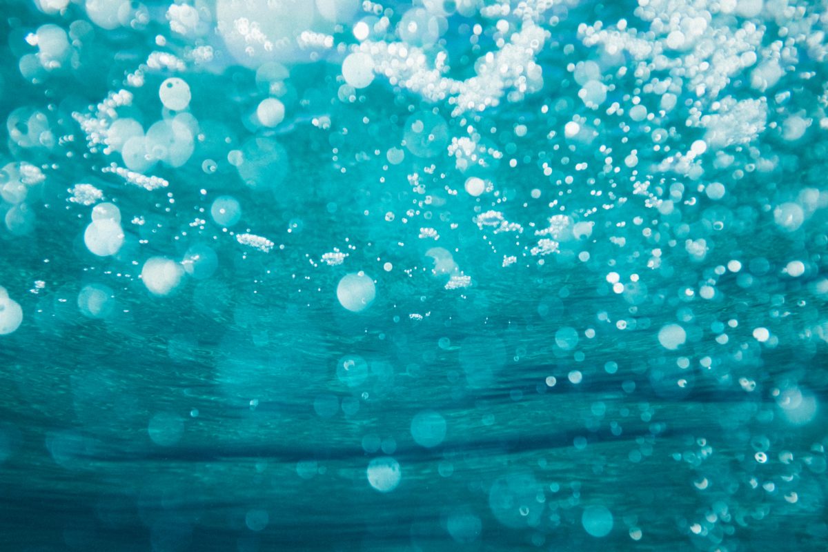 Eau turquoise avec des bulles dans un océan bleu ou un lagon avec des vagues douces et montrant un courant marin